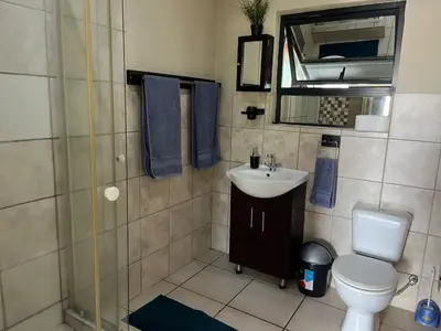 a bathroom with a sink and a toilet and a mirror at Cute Tranquil Pool Side Apartment in Cape Town