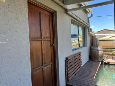 a door to a house with a porch and a swimming pool at Cute Tranquil Pool Side Apartment in Cape Town