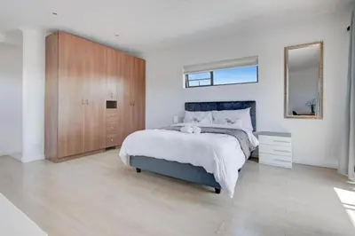 a bedroom with a large bed and a wooden cabinet at Spacious Room with Balcony, Mountain Views, Modern Bathroom Tub and Shower and WiFi and Pool view in Cape Town