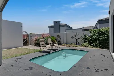 a swimming pool with two chairs in a yard at Spacious Room with Balcony, Mountain Views, Modern Bathroom Tub and Shower and WiFi and Pool view in Cape Town