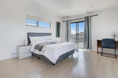 a bedroom with a bed and a desk and a window at Spacious Room with Balcony, Mountain Views, Modern Bathroom Tub and Shower and WiFi and Pool view in Cape Town