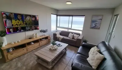 a living room with a couch and a table at Beachfront Apartment with Amazing Views on Kite Surfing Beach in Cape Town