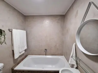 a bathroom with a tub and a round mirror at Beachfront Apartment with Amazing Views on Kite Surfing Beach in Cape Town