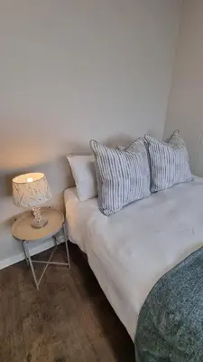 a bedroom with a bed and a table with a lamp at Beachfront Apartment with Amazing Views on Kite Surfing Beach in Cape Town