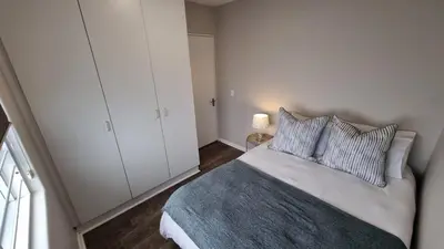 a bedroom with a bed and a white cabinet at Beachfront Apartment with Amazing Views on Kite Surfing Beach in Cape Town