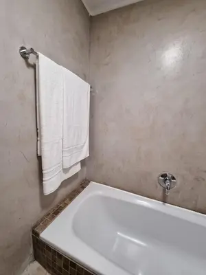 a white bath tub in a bathroom with white towels at Beachfront Apartment with Amazing Views on Kite Surfing Beach in Cape Town