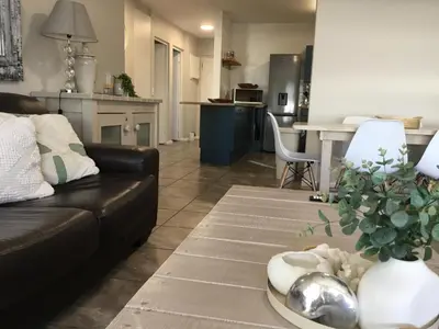 a living room with a black couch and a kitchen at Beachfront Apartment with Amazing Views on Kite Surfing Beach in Cape Town