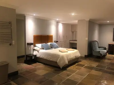a bedroom with a large bed and a chair at 82 on Second family stay in Kleinmond