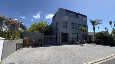 a white house with palm trees in front of it at 82 on Second family stay in Kleinmond