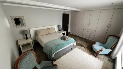 a bedroom with a bed and two chairs at 82 on Second family stay in Kleinmond