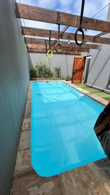 a blue swimming pool with a pergola at 82 on Second family stay in Kleinmond