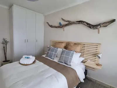 a bedroom with a bed with a branch on the wall at Featherbed in Hermanus