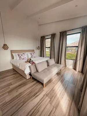 a bedroom with a bed and a couch and windows at 155 Hangklip self catering in Pringle Bay