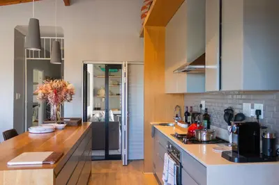 a kitchen with white cabinets and a wooden counter top at MOS- Palmiet in Kleinmond