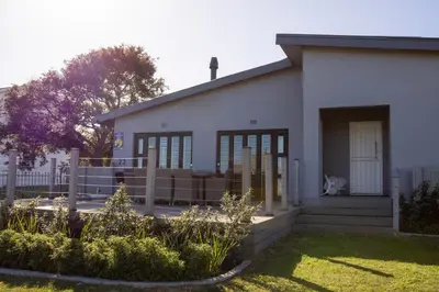 a white house with a fence and a yard at MOS- Palmiet in Kleinmond