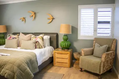 a bedroom with a bed and a chair and birds on the wall at MOS- Palmiet in Kleinmond