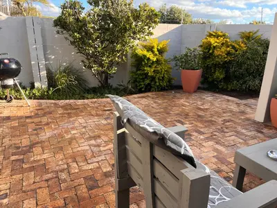 a patio with a bench on a brick patio at Cozy Cottage in Cape Town
