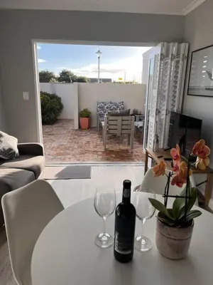 a white table with two glasses and a bottle of wine at Cozy Cottage in Cape Town