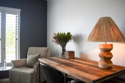 a room with a table with a lamp and a chair at MOS-Palmiet 72 in Kleinmond
