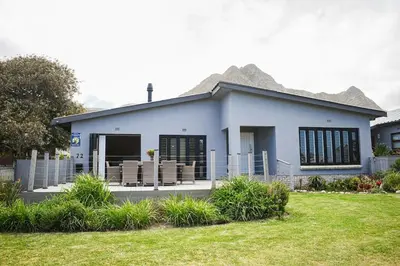 a blue house with mountains in the background at MOS-Palmiet 72 in Kleinmond
