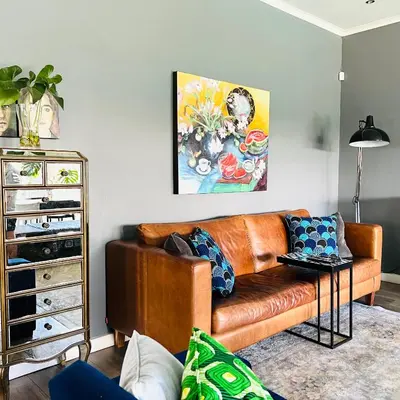 a brown leather couch in a living room with a painting at Spacious Stays Residence in Paarl