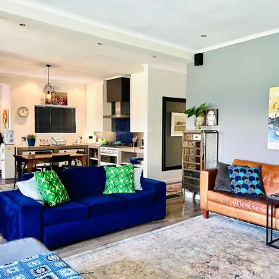 a living room with a blue couch and a kitchen at Spacious Stays Residence in Paarl