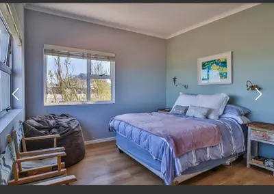 a bedroom with a bed and a window at OceansCrest Seaview Apartment in Bettyʼs Bay