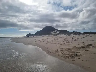 a beach with a mountain in the background with people on it at OceansCrest Seaview Apartment in Bettyʼs Bay