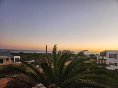 a view of the sunset from the balcony of a house at OceansCrest Seaview Apartment in Bettyʼs Bay