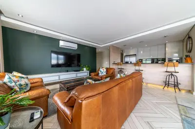 a living room with brown leather furniture and a kitchen at Apartment 206 Andringa Walk in Stellenbosch