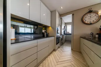 a kitchen with white cabinets and a clock on the wall at Apartment 206 Andringa Walk in Stellenbosch