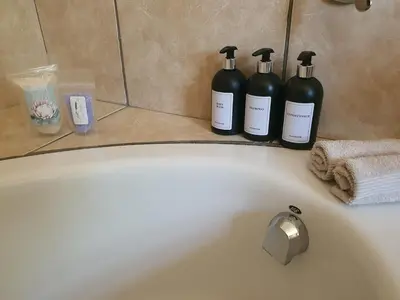 three bottles of wine sitting on the edge of a bath tub at Lynwood Place in Cape Town