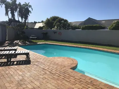 a swimming pool with a bench next to a fence at Bright apartment in Cape Town