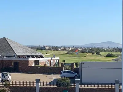 a building with two cars parked in a parking lot at Bright apartment in Cape Town