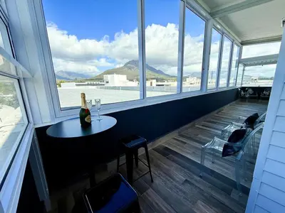 a wine bottle on a table in a room with windows at Dior Maison de Reve- Private Penthouse in Stellenbosch
