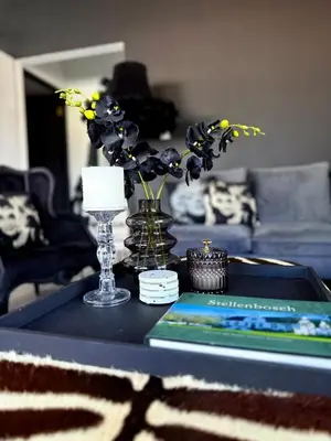 a table with a vase of flowers and a book at Dior Maison de Reve- Private Penthouse in Stellenbosch