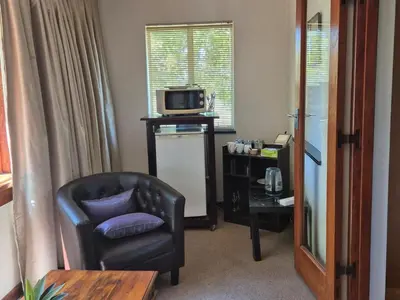 a living room with a chair and a microwave at Afton Safari Lodge in Cape Town