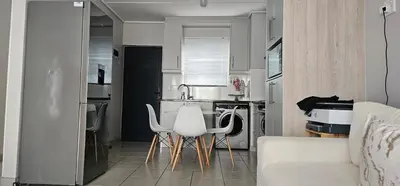 a kitchen with two white chairs and a kitchen sink at 33 Langeberg Heights in Cape Town