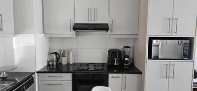 a kitchen with white cabinets and a stove top oven at 33 Langeberg Heights in Cape Town
