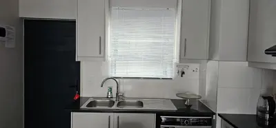 a kitchen with white cabinets and a sink and a window at 33 Langeberg Heights in Cape Town
