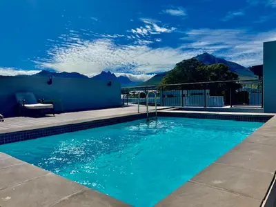 a blue swimming pool with mountains in the background at 18 on The Den Studio Apartment in Stellenbosch