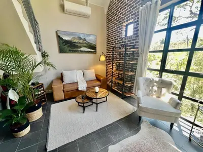 a living room with a couch and a chair at Enchanted View from Above in Stellenbosch