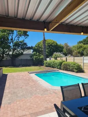 a swimming pool under a pergola with a patio at Flamingle at Coot in Cape Town