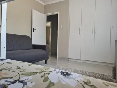 a living room with a bed and a couch at Flamingle at Coot in Cape Town