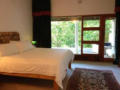 a bedroom with a bed and a large window at Tolbos Grand in Somerset West