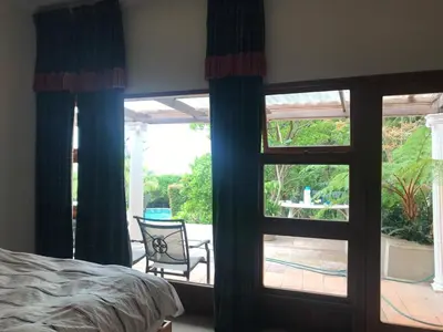a bedroom with a window with a view of a patio at Tolbos Grand in Somerset West