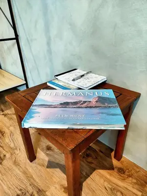 two books sitting on top of a wooden table at Tide's whisper in Hermanus
