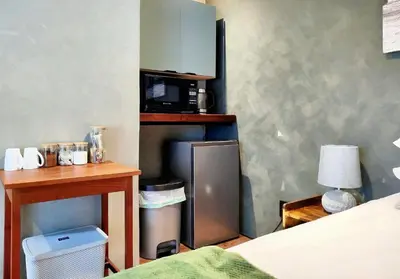 a room with a bed and a desk and a microwave at Tide's whisper in Hermanus