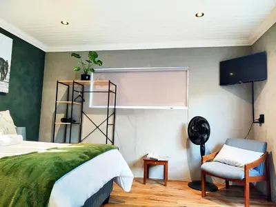 a bedroom with a bed and a chair in a room at Tide's whisper in Hermanus