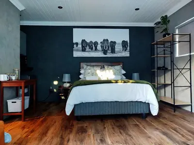 a bedroom with a bed with a painting of elephants on the wall at Tide's whisper in Hermanus